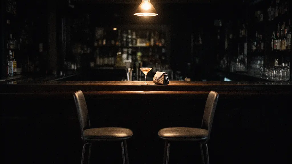 Vue d'ensemble d'un coin de bar intime faiblement éclairé avec deux tabourets rapprochés évoquant le scénario de la première rencontre rejouée